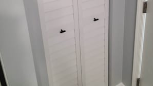 Een witte kast met horizontale latten en twee zwarte handgrepen.