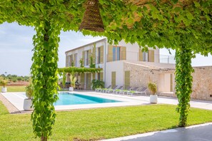 A poolside area with a clear view of a building, a swimming pool, and a pergola covered with green vines. - CAN MOSCA - Fabulous villa with private pool - Free Wifi (Manacor)