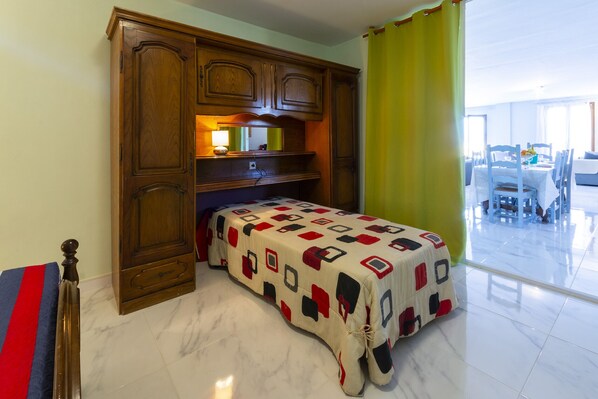 Habitación de hotel con cama, armario de madera y zona de comedor con mesa y sillas.