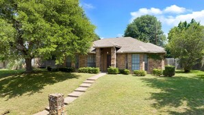 A single-story brick house with a front yard, a stone mailbox, and a clear blue sky. - Spacious 2BR home near Downtown Dallas and State Fair of Texas (Dallas)