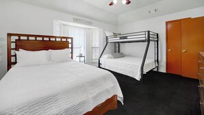 A bedroom with a large bed, a bunk bed, a ceiling fan, and a door. - Spacious 2BR home near Downtown Dallas and State Fair of Texas (Dallas)
