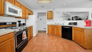 A kitchen with wooden cabinets, a microwave, stove, oven, and dishwasher. - Spacious 2BR home near Downtown Dallas and State Fair of Texas (Dallas)