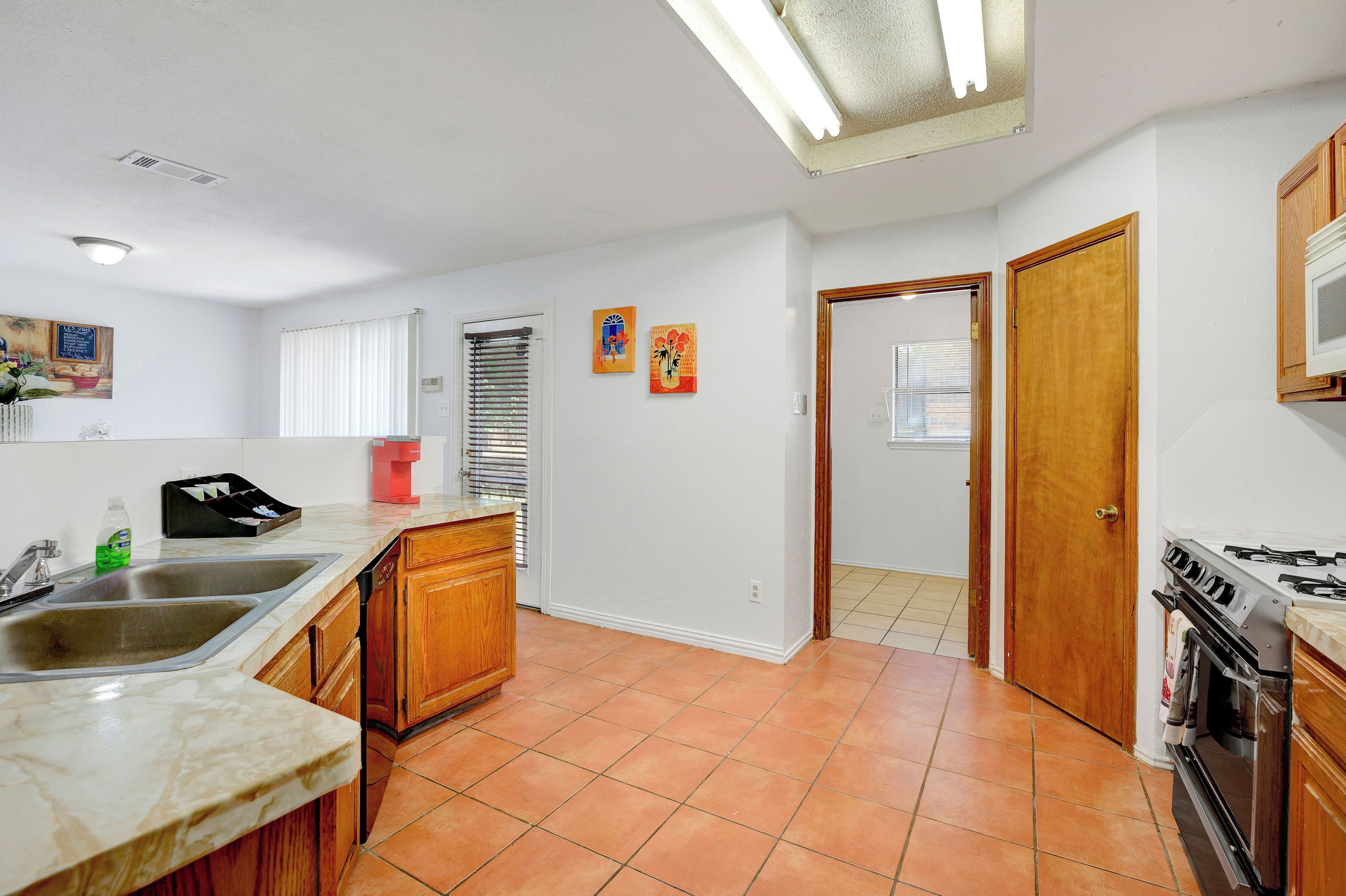 Una cocina con estufa, pileta y armarios de madera. Dos puertas dan acceso a otras habitaciones.