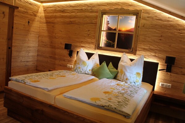 Una habitación tipo cabaña de madera con dos camas, una ventana y vistas al atardecer, además de un cabecero de madera.