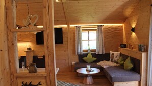 A cozy wooden cabin interior with a sofa, a small table, and a wooden cabinet. - Ferienwohnung Almstüberl mit Südbalkon, 1-3 Personen, 50 qm (Bad Reichenhall)