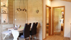 A wooden interior with a dining table, chairs, and a hanging light fixture. - Ferienwohnung Almstüberl mit Südbalkon, 1-3 Personen, 50 qm (Bad Reichenhall)
