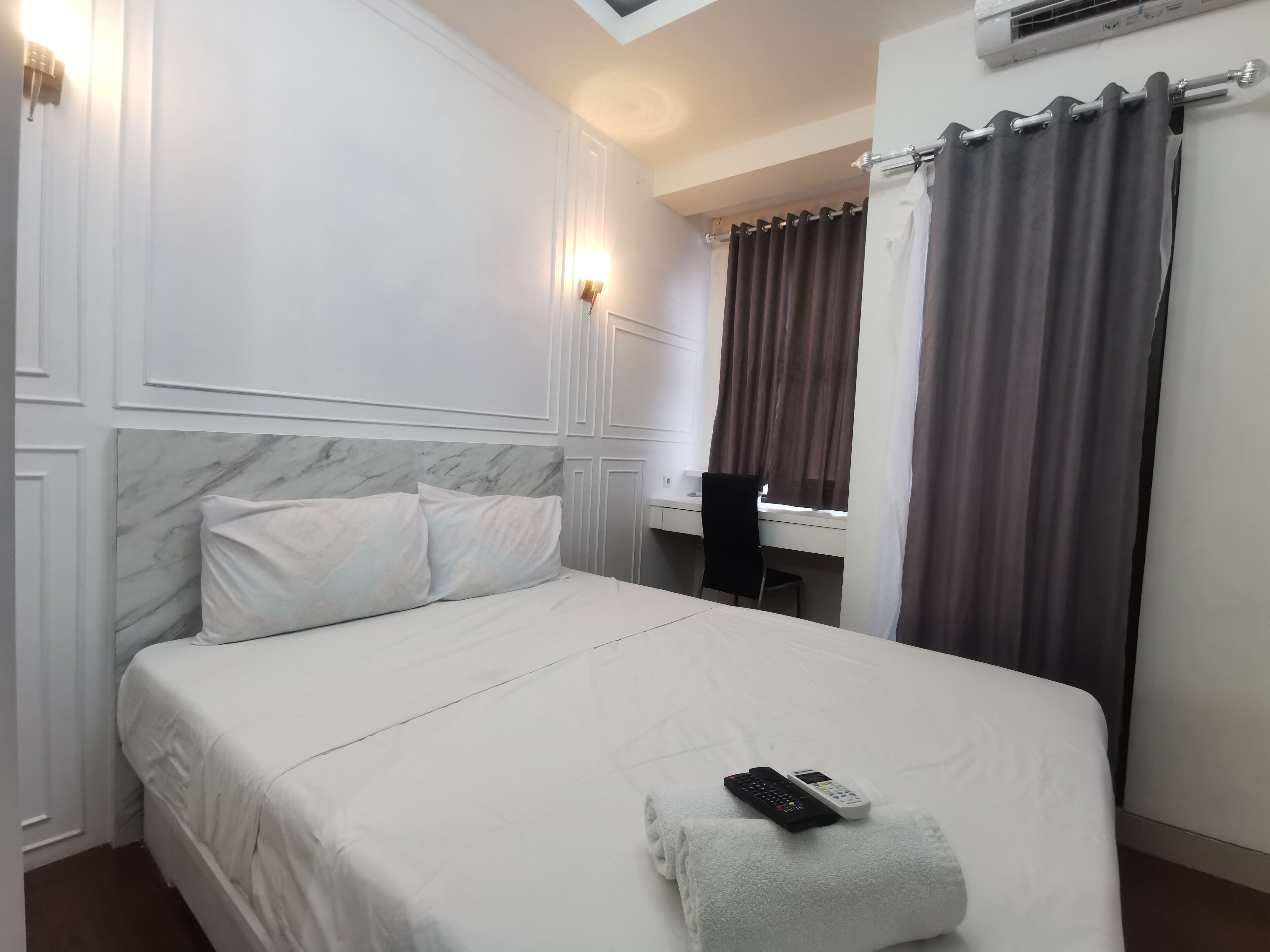 Une chambre d’hôtel avec un lit, un bureau et une fenêtre avec des rideaux.