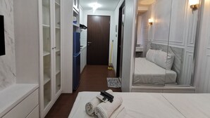A hotel room with a bed, a mirror, a wardrobe, a bathroom, and a hallway. - ARSAKHA 003 Transpark cibubur By Karlina (Depok)