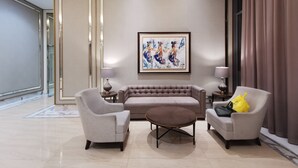 A modern living room with a beige sofa, two armchairs, and a coffee table. There is a framed artwork on the wall and a lamp on each side of the sofa. - ARSAKHA 003 Transpark cibubur By Karlina (Depok)