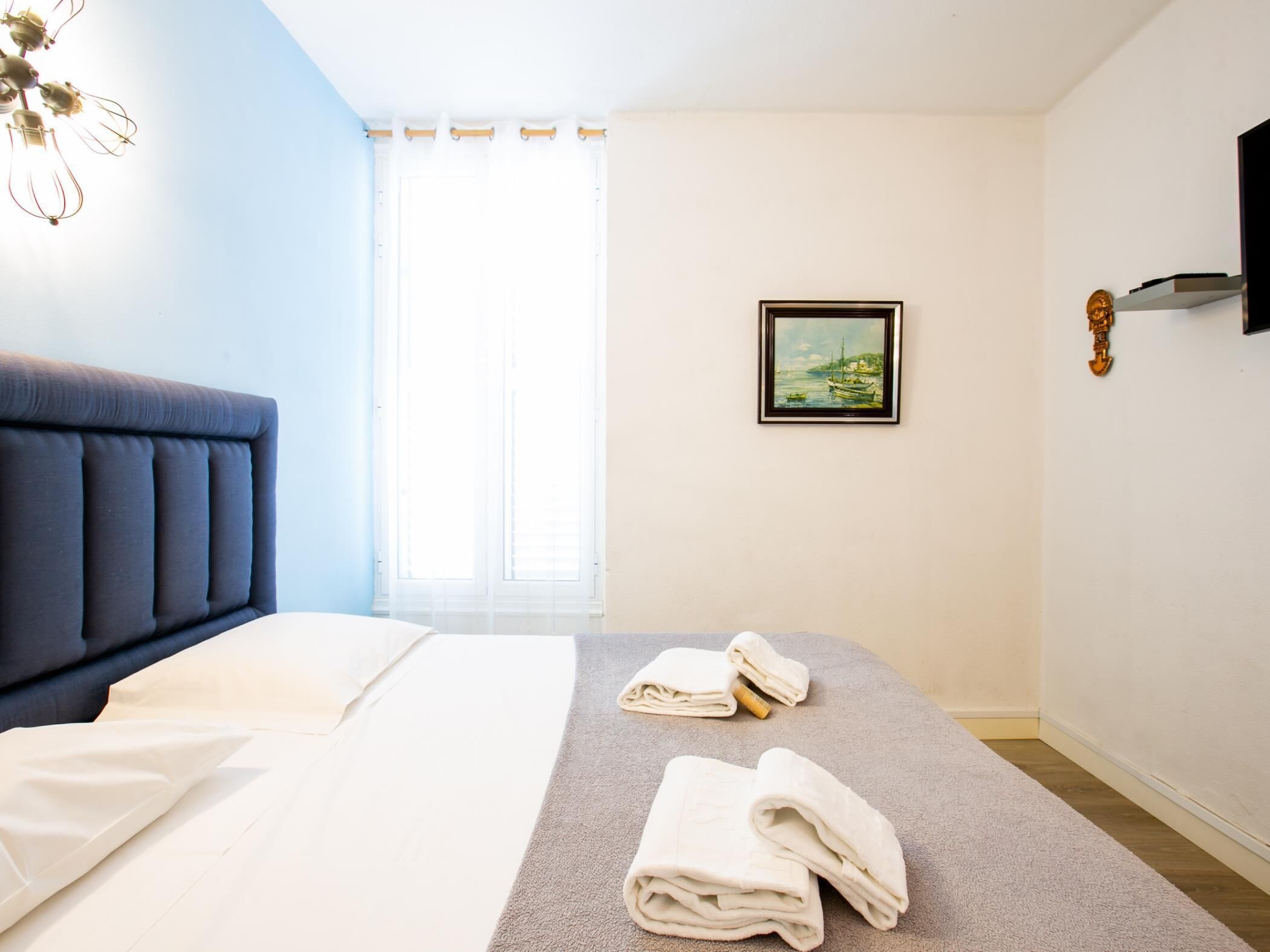 A hotel room with a bed, a painting, and towels on the floor.