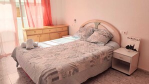Ein Schlafzimmer mit einem Bett, einem Nachttisch, einer Kommode und einem an der Wand hängenden Bild.