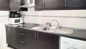Eine moderne Küche mit dunklen Schränken, einer Mikrowelle, einer Kaffeemaschine, einem Spülbecken und einem Geschirrspüler.