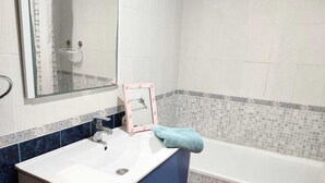 Ein Badezimmer mit einem weißen Waschbecken, einem Spiegel und einer Badewanne.