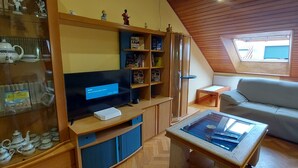 A cozy living room with a TV, wooden shelves, a sofa, and a coffee table. - Apartamento Sleeps 6 with Garage (Cambados)