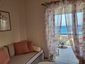 Ein Zimmer mit einer Couch, blumigen Vorhängen und Meerblick.