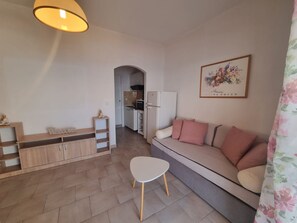 Ein modernes Wohnzimmer mit einer Couch, einem kleinen Tisch und einer Küche im Hintergrund.