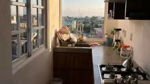 A narrow kitchen with a view of the city through large windows.