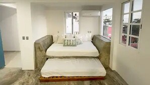 A bedroom with a bed, a window, and a view of the outside.