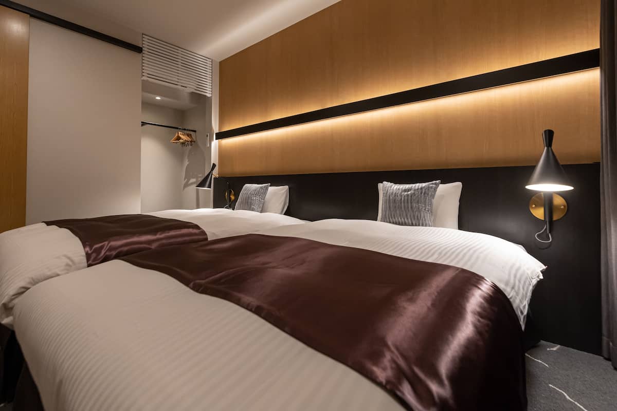 Une chambre d’hôtel avec un grand lit, une lampe de chevet et une tête de lit en bois.