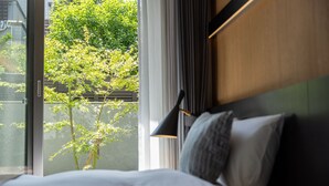 A hotel room with a bed, a window with a view of greenery, and a lamp. - Hotel Liberte Kyoto Gojo (Kyoto)