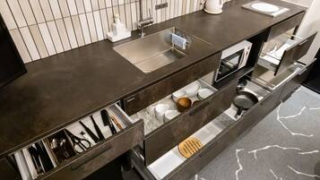 A modern kitchen with a dark countertop, stainless steel sink, and built-in appliances.