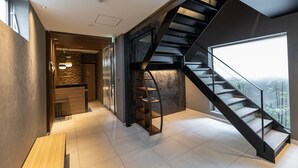 A modern interior with a staircase, a wooden bench, and a view through a large window. - Hotel Liberte Kyoto Gojo (Kyoto)