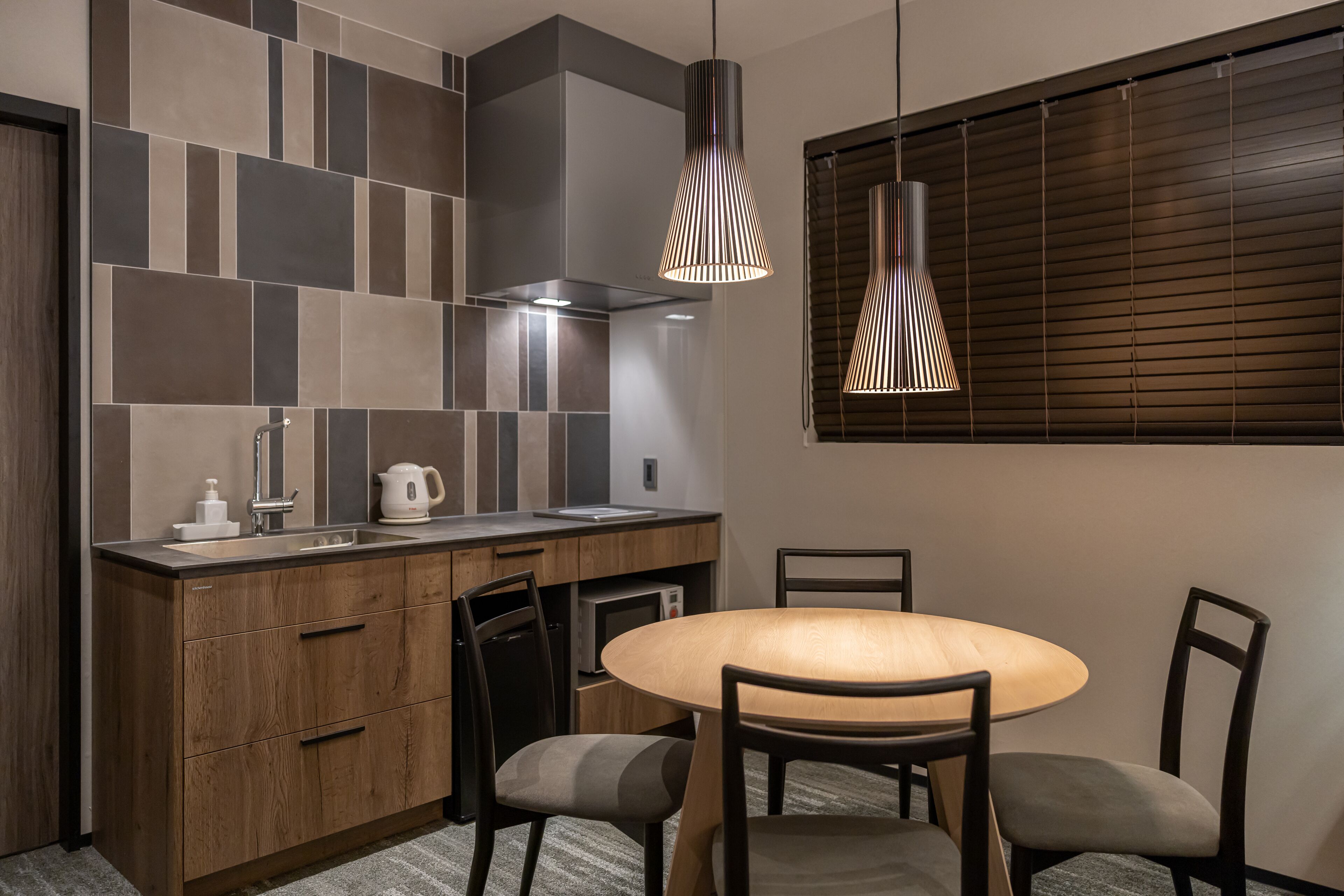 Cocina moderna con encimera de madera, microondas integrado y una mesa redonda con cuatro sillas.