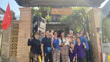 A group of people posing in front of a building entrance with a sign that reads "My Home Hue Vacations."