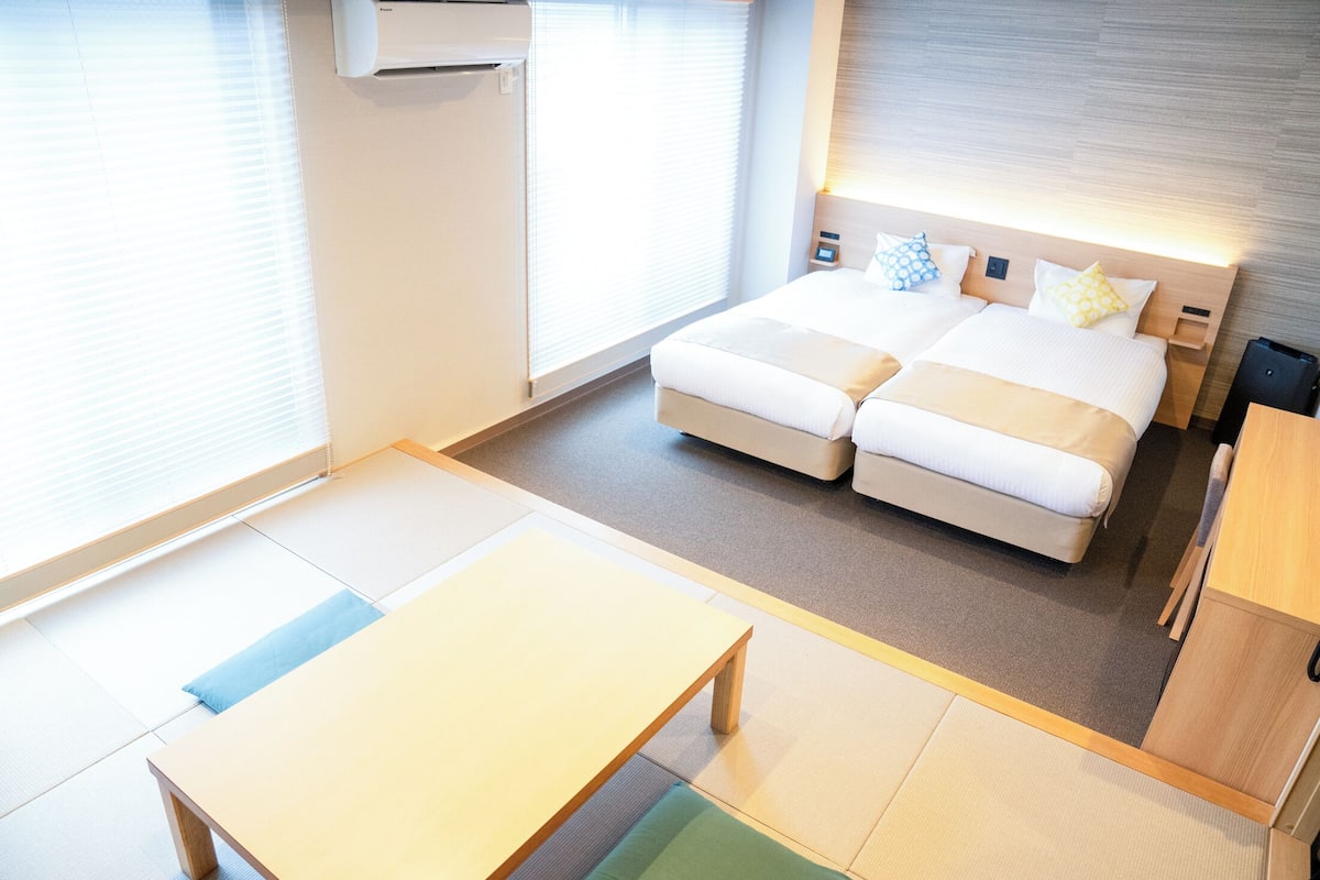 Une chambre d’hôtel moderne avec un grand lit, une petite table et un futon.