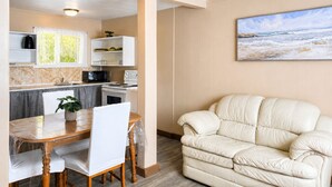 A compact living space with a kitchenette, dining area, and a sofa. - Cozy 2BR Cottage • Walk to Beach 1 • Free Parking & WiFi (Wasaga Beach)