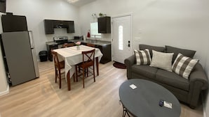 Un espacio habitable compacto con kitchenette, comedor y zona de estar.