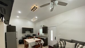 Un espacio habitable compacto con kitchenette, comedor y sofá.
