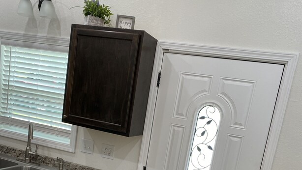 Una cocina con un armario de madera oscura, encimera de granito, pileta de acero inoxidable y una mesa de comedor con mantel blanco.