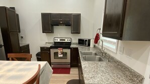 Una cocina compacta con armarios oscuros, microondas integrado, estufa y lavaplatos.