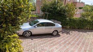 A parked car on a paved driveway with a building in the background.