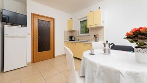 A compact kitchen with a dining area, a television, and a coffee machine.