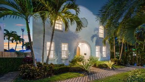 Uma casa com um caminho de pedras que leva à entrada, cercada por palmeiras e vegetação bem cuidada.