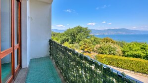 A balcony with a view of the sea and mountains, a green patterned floor, and a metal railing. - La Finestra Sul Lago: Lake Maggiore View & Garden, Stresa, Italy (Stresa)