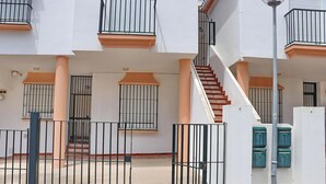 Un immeuble résidentiel à plusieurs étages, doté de balcons, d’un escalier et d’une entrée sécurisée par un portail.