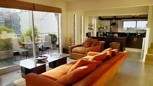 En moderne stue med en sofa, et glasbord og et spiseområde med stole.