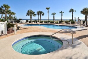 Uima-allas, jossa on pieni poreallas, ja allasta ympäröivät palmuja. Sieltä on näkymä merelle.