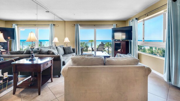 A spacious living room with a large window offering a view of the ocean, a comfortable sofa, a coffee table, and a flat-screen TV. - Destin Towers 32 (Destin)