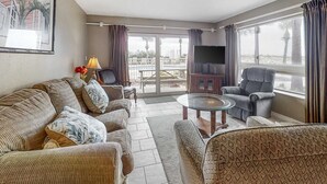A living room with a sofa, armchairs, a coffee table, and a TV.