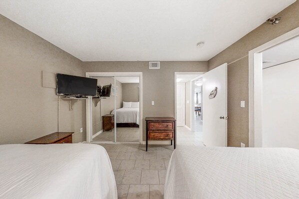 A hotel room with two beds, a television, and a mirror. - Destin Towers 1C (Destin)