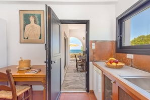 Una cocina con comedor, vista al mar y una cesta de frutas en la encimera.