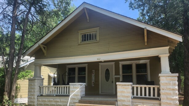 Ein zweistöckiges Haus mit Veranda, Säulen aus Stein und der Hausnummer 422.
