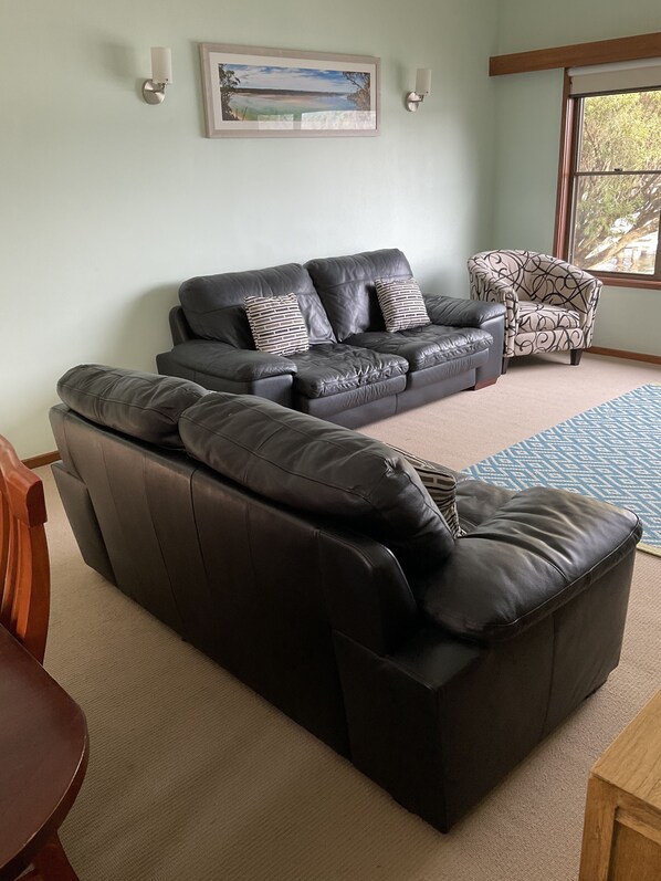 Relax in this stylish living room with a comfortable sofa, a dining table, and a beautiful painting.