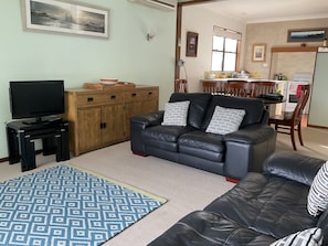 Relax in the living room with a comfortable sofa, striped pillows, and a TV on a stand.