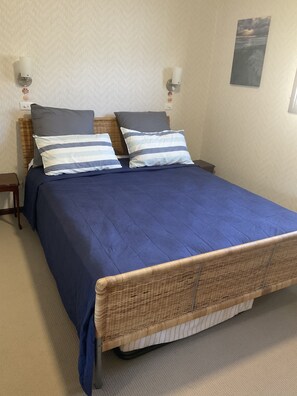 Cozy retreat with a large bed, wall-mounted lights, and a framed picture.