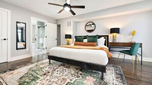 A modern bedroom with a large bed, a desk, a chair, and a ceiling fan. - ★ HostWise Stays ★ Rooftop Deck & Fire Pit Haven | Theater & Balcony (Pittsburgh)